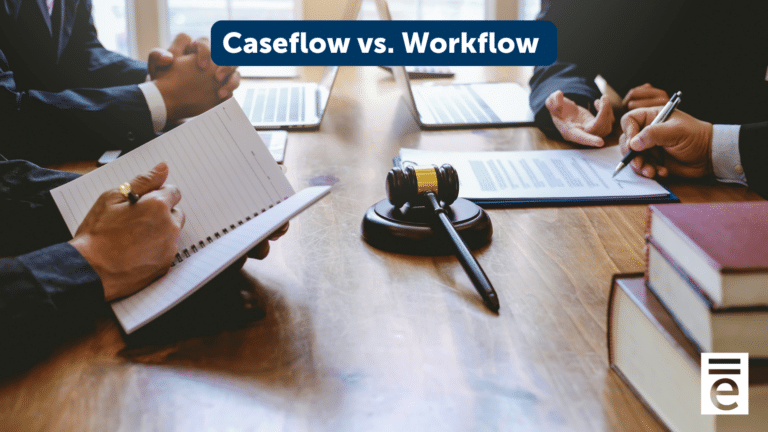 Two people sitting at a conference room table with books and a gavel in the middle of the table