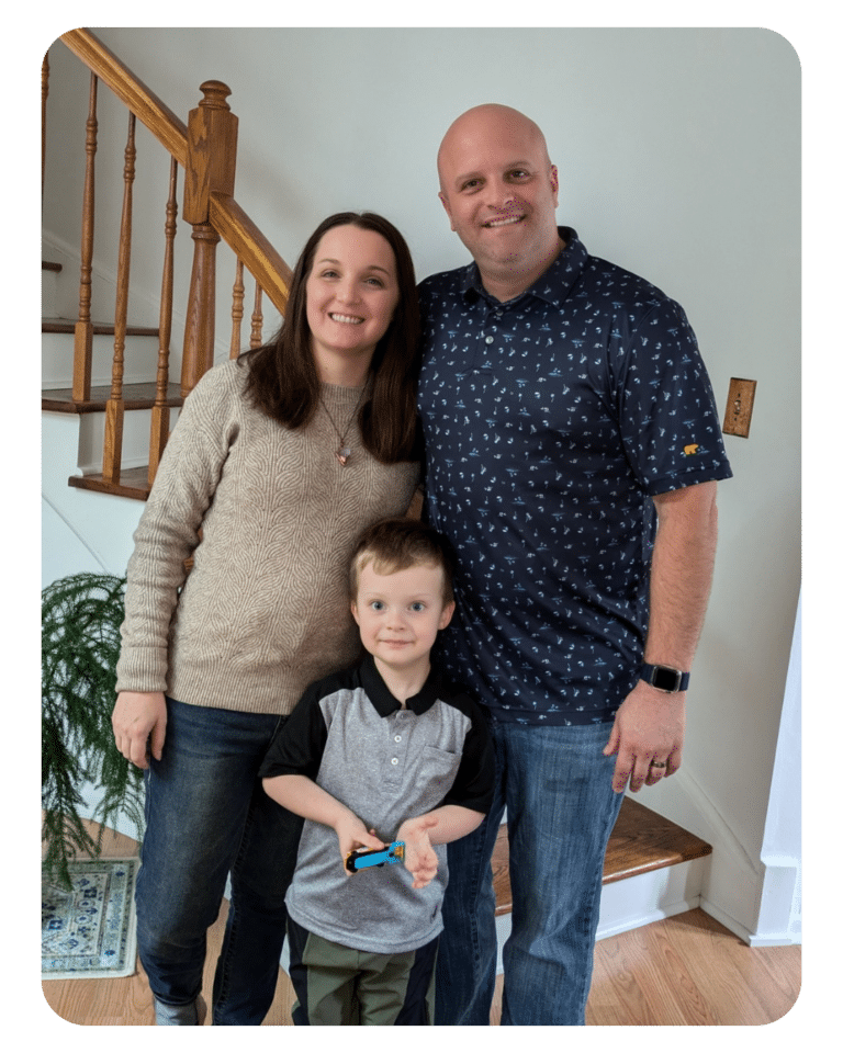 Picture of our Account Executive, Colleen Bement, and her family. Her husband is standing to the right of her and her four-year-old son is standing in front of them between the two.